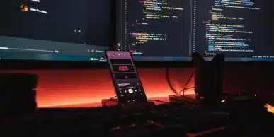 Écrans de code et smartphone illustrant la pile d'outils de supervision d'un système d'information