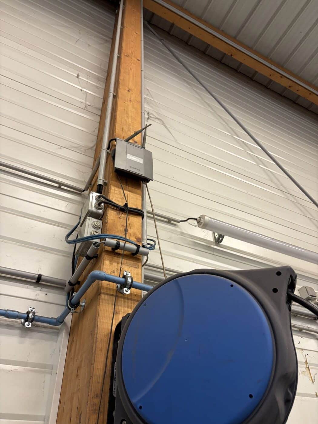 Borne WiFi professionnelle installée sur une poutre en bois dans un atelier automobile